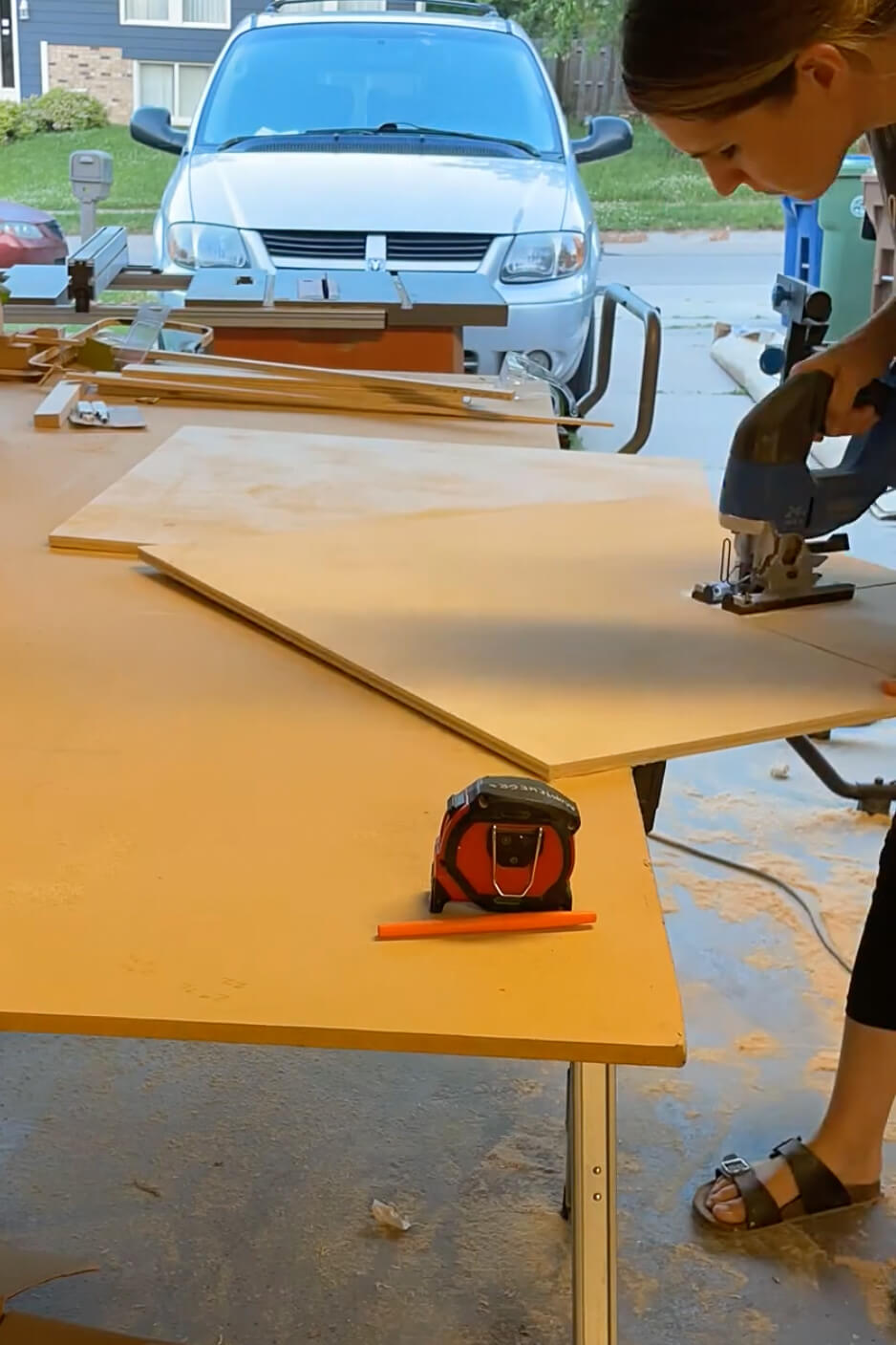 Woman using a jig saw to build DIY kitchen cabinets.